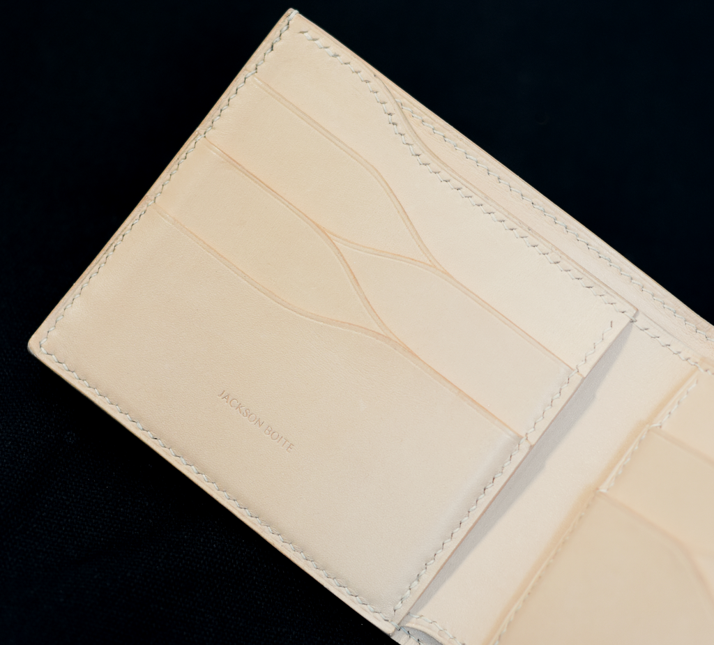 Inside of handmade 8-card bifold wallet in vegetable-tanned leather showing curved card pockets and white linen thread saddle stitching — Jackson Boite