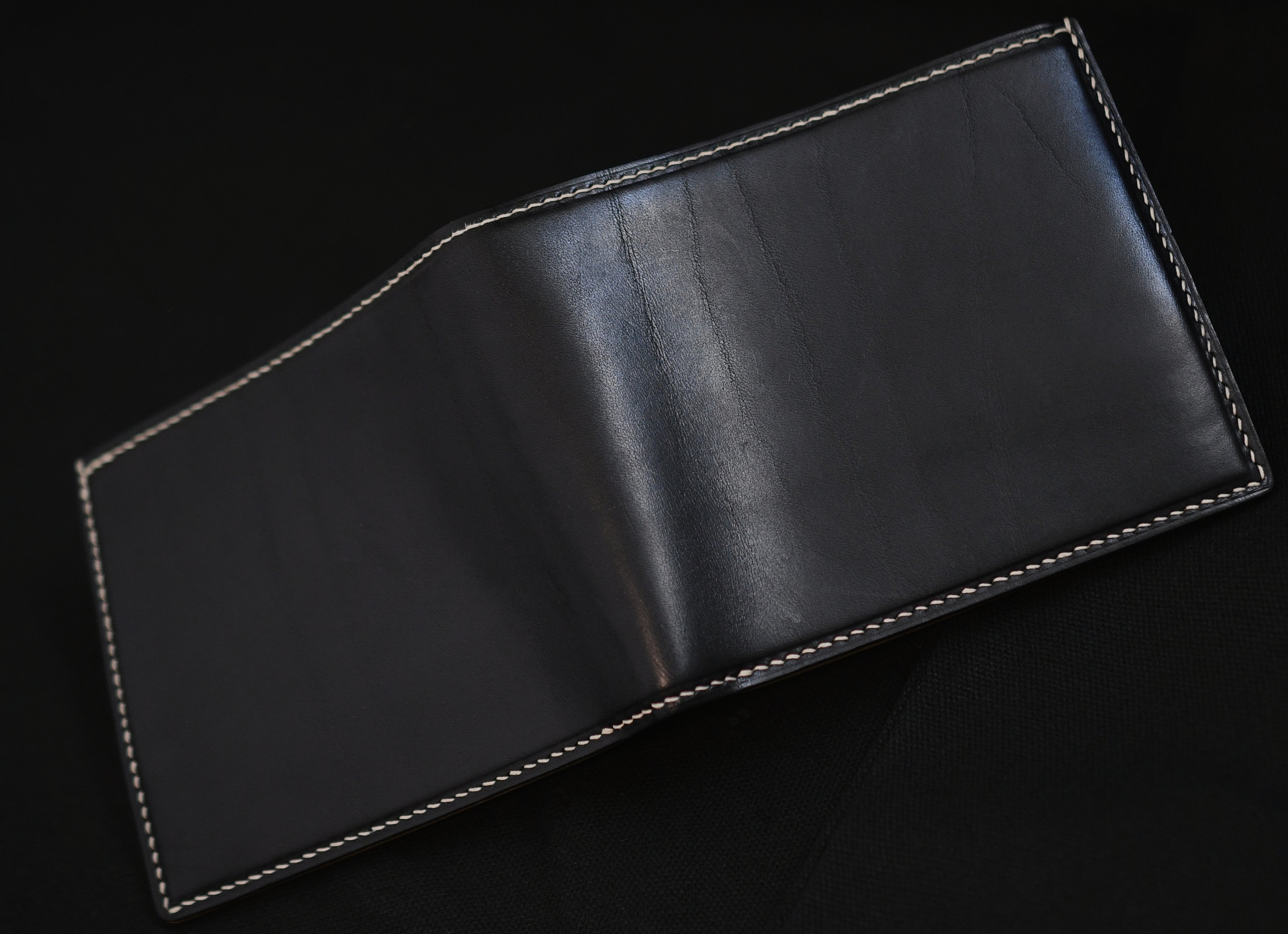 Outside of opened handmade bifold wallet in aged Vachetta leather with natural patina wrinkles and white linen thread hand-stitching — Jackson Boite