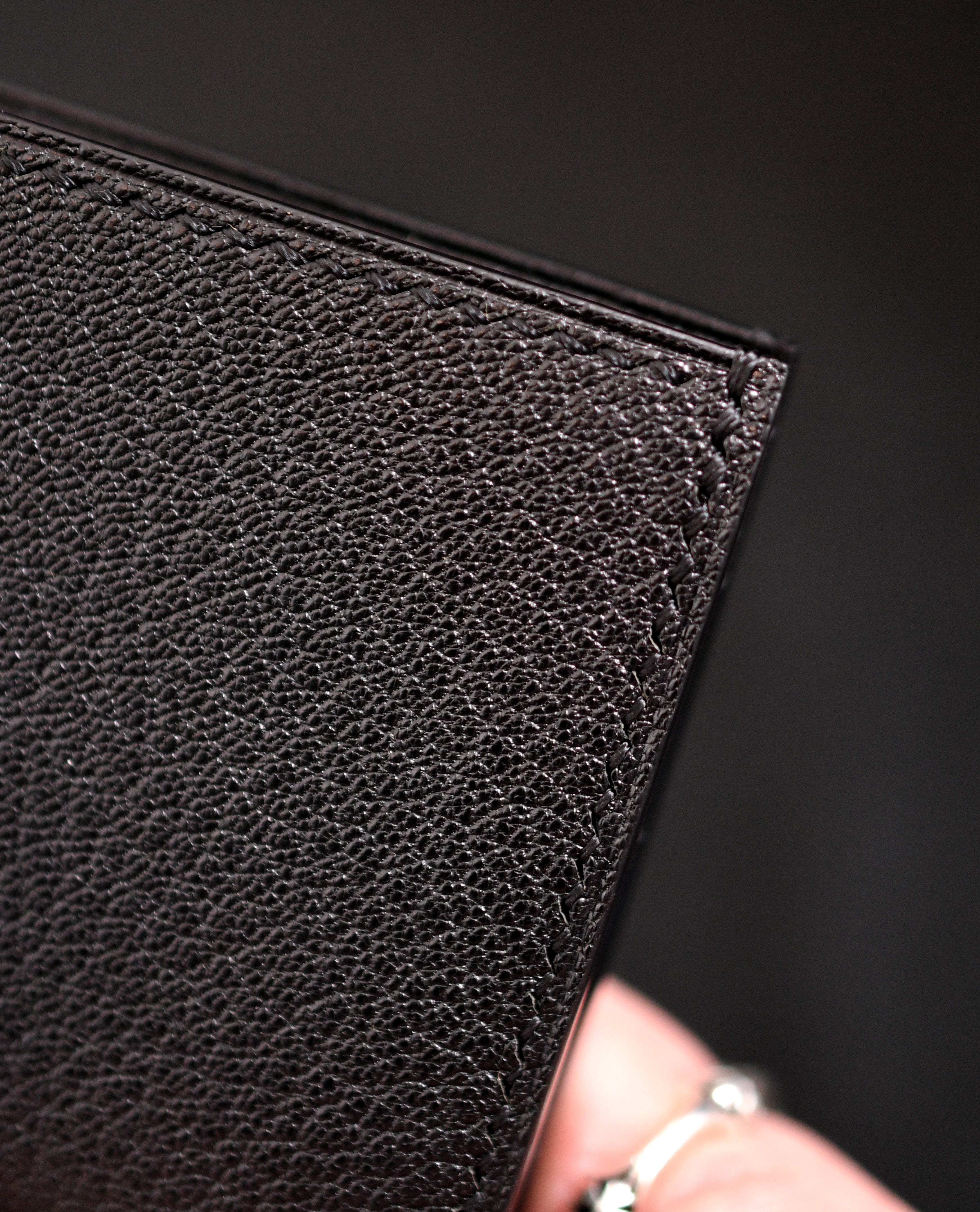 Close-up of handmade black chèvre bifold wallet in Alran Sully Noir showing leather grain, saddle stitching, glossy painted and heat-creased edges — Jackson Boite